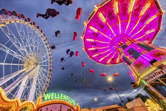 Chain carousel and Ferris wheel in the evening. 177th Cannstatter Volksfest at the Cannstatter