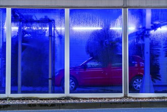 Car in an automatic car wash, car wash tunnel, cleaning foam is sprayed on, rotating brushes clean