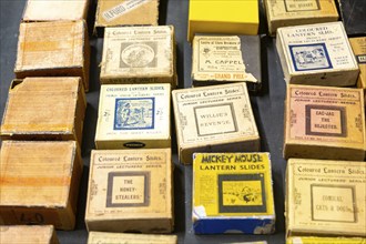 Boxes of commercial magic lantern slides on table top display, UK