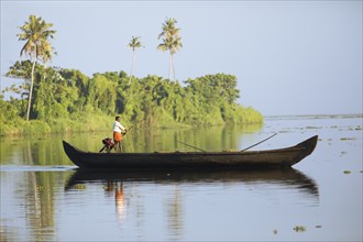 Fisherman in the morning with a boat on the Vembanad Lake, canal system of the backwaters, Kerala,