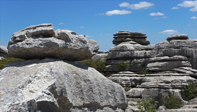 Large boulders under a blue sky with light clouds and scattered vegetation, karst mountains, Torcal