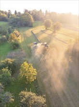 Picturesque fields at sunset, where machines stir up dust during the harvest, Haselstaller Hof,