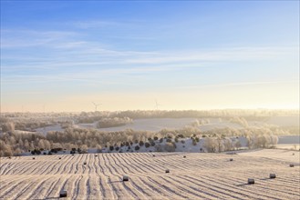 Scenics view in a rural winter landscape with bales on a snowy field a cold winter day, Sweden,