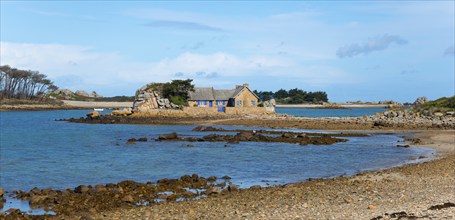 A stone house on a small island surrounded by calm water and rocks, house on the Plage de Raluzet,