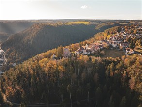 Village with historic buildings on a hill covered in colourful autumn forest, Zavelstein, Black