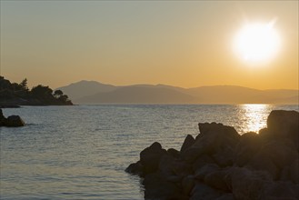 Sunset over the sea, silhouettes of rocks and mountains, warm colours, Agíos Nikólaos, Agios