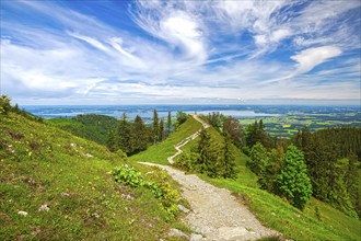 A hiking trail runs along a mountain ridge to Lake Chiemsee with a picturesque view of the