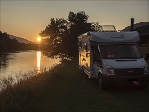 Camper van parked for the night at river bank of river Lagen, at sunset, some km south of Dombas,