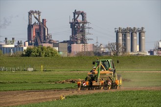 Farmer working in the field, Duisburg-Baerl, sowing, in the background the ThyssenKrupp Steel blast