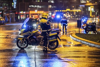 Policeman with motorbike, in rainy weather, blocking a road, police motorbike with blue light