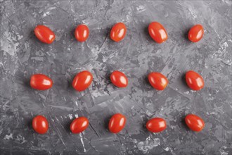 Rows of cherry tomatoes on a black concrete background, top view, flat lay