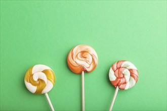 Three lollipop candies on green pastel background. copy space, top view, flat lay