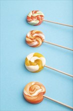 Four lollipop candies on blue pastel background. copy space, side view