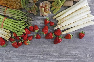 Green asparagus, white asparagus and fresh strawberries decorated on a rustic wooden table