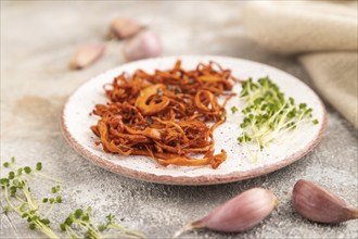 Fried Cordyceps militaris mushrooms on brown concrete background with microgreen, herbs and spices.