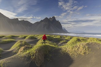 Hiker looking over the Vestrahorn, Vesturhorn, made of gabbro and granophyre rocks, part of the