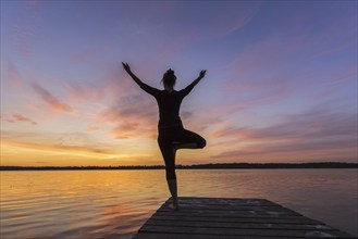 Woman practicing standing posture Vrikshasana, Tree Pose, one legged balancing asana of the