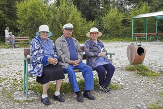 Local elderly Russians resting on bench along Lake Baikal in summer, Southern Siberia, Russia,