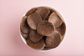 Chocolate chips with caramel on pink pastel background. top view, flat lay, close up