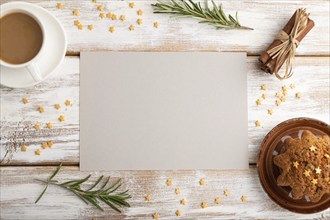 Gray paper sheet mockup with cup of coffee and cake on white wooden background. Blank, top view,