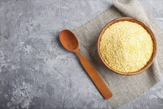 Wooden bowl with cornflakes and a wooden spoon on a gray concrete background. linen napkin, top