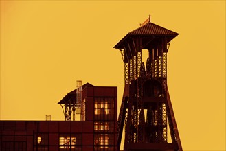 Colliery headframe, hoist frame and coal mine building in the coal mining town Beringen at sunset,