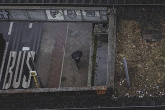 A person in Schöneberg walks with an umbrella on a pavement in Berlin, 22/03/2024