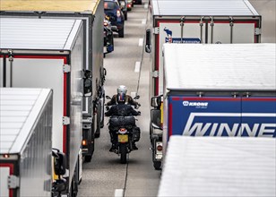 Motorcyclists squeeze past in the middle of the road between vehicles, in a 9 km long traffic jam