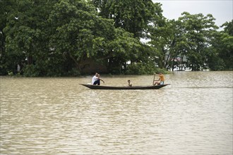 Morigaon, India. 4 July 2024. People travel in a boat to cross a flooded area, in a flood affected