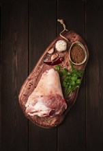 Raw pork knuckle, on a wooden chopping board, with spices, close-up, top view, no people