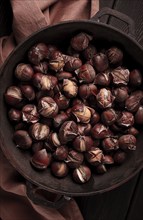 Roasted chestnuts, in an iron pan, wooden table, top view, no people, rustic style