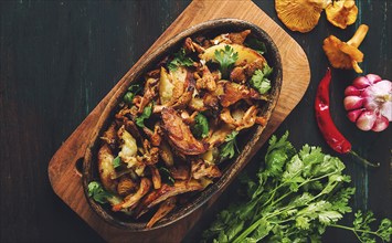 Fried chanterelles with mushrooms, in a clay pan, close-up, top view, selective focus