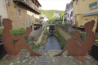 Two rusty figures reading a book on the bridge over the Gießen stream, sitting, rusty, brown, boy,