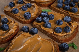 Rye bread with peanut paste and fresh blueberries, top view, no people