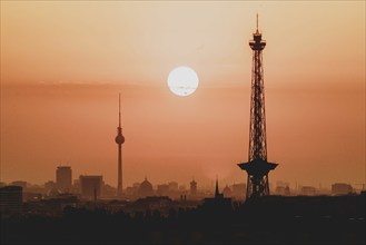 The sunrise emerges behind the city skyline with the television tower and the radio tower in