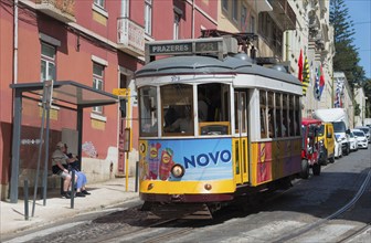 A yellow-purple tram with Novo advertising runs along the street with people in the background,