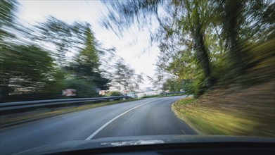 A winding road with trees in the background, conveying speed and movement, symbolised by