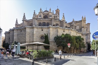 Church façade with tourists and open-air café on a sunny day in a busy street, Granada