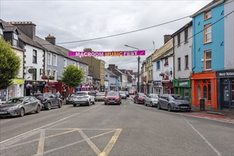 Lively city street with colourful houses and music festival advertising, urban flair, Macroom