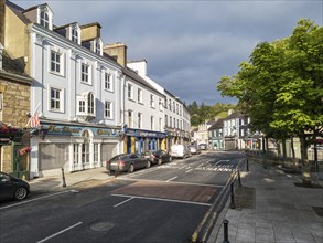 Historic street with striking buildings and trees in the sunlight, Donegal