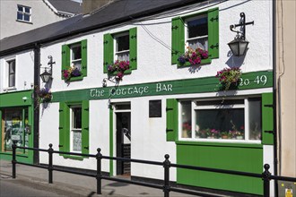 White and green pub on a quiet street decorated with flowers, Letterkenny