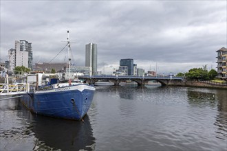 Ship in the harbour with a view of a bridge and urban buildings in cloudy weather, Belfast