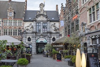 Historic building with ornate façade and cafés on a busy street, Ghent