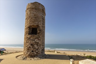 Stony old tower on the beach, surrounded by sand and sea, under a bright blue sky, Puerco