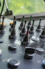 Close-up of a control panel with various levers and buttons, surroundings blurred, track