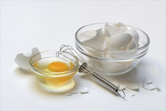 Egg whites and egg yolks in glass bowl and egg shells, whisk