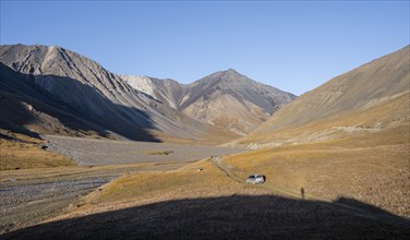 Off-road vehicle on a track in the Burkhan valley, mountain landscape with golden meadows, Terskey