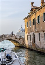 Young man standing on a bridge over a canal, behind the church Chiesa del Santissimo Redentore,