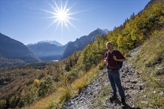 Mountaineers on a mountain hiking trail, Rinnkendlsteig, autumn forest and snow-covered mountains,