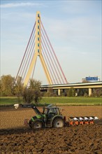 Farmer ploughing a field, tractor with plough, near Neuss, Fleher motorway bridge, A46, North